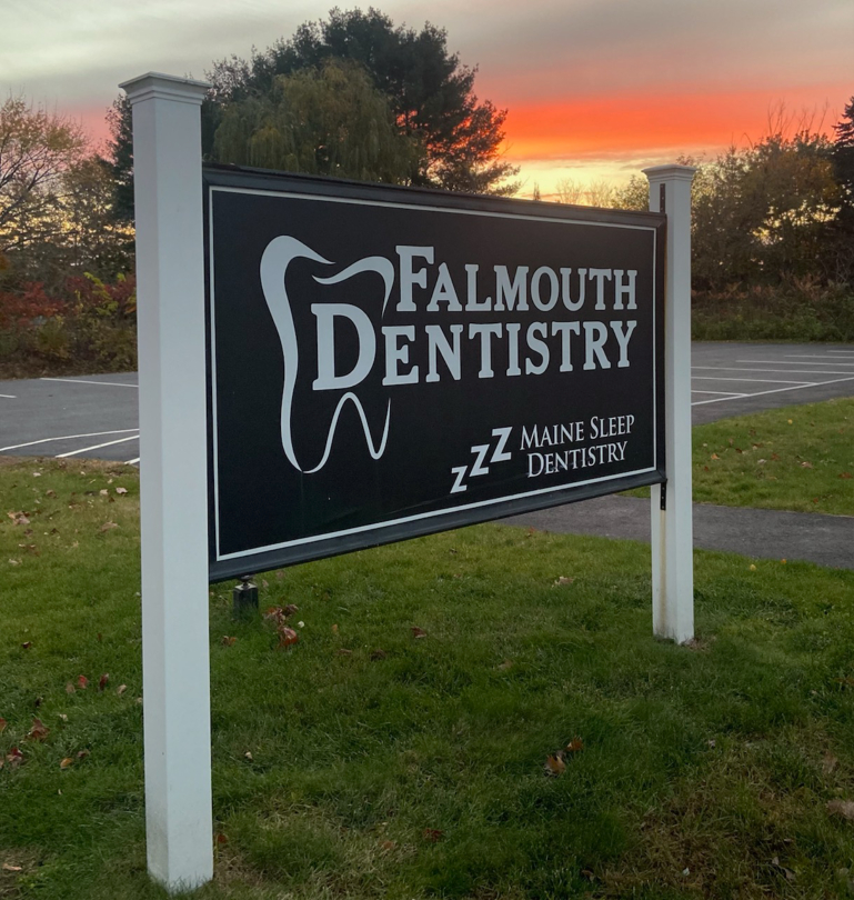 Falmouth Dentistry sign outdoors with sunset in background