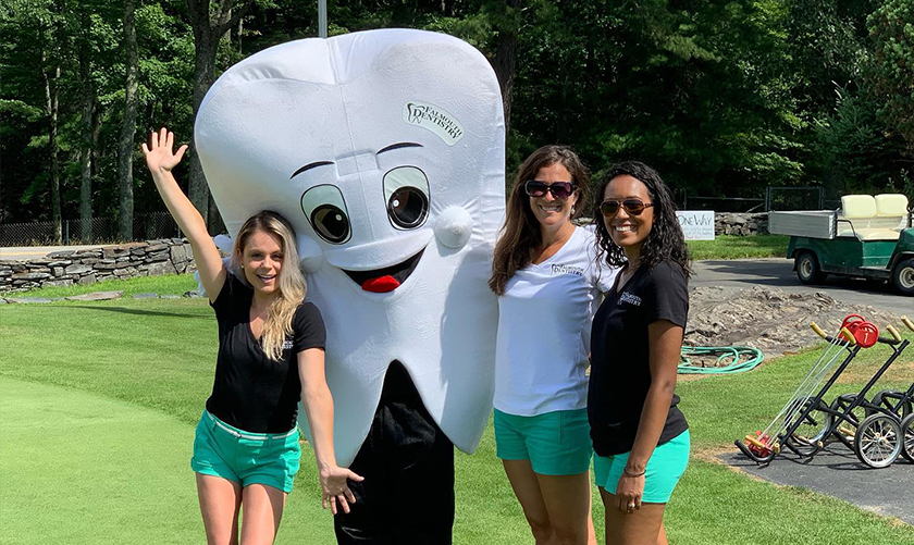 Three dental team members with tooth mascot