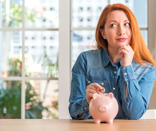 woman putting a coin into a piggy bank