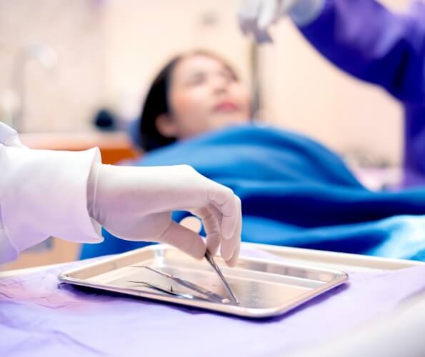 Falmouth emergency dentist grabbing a dental tool off of a tray while treating patient