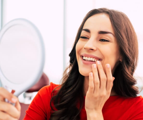 Dental patient admiring her smile in a mirror