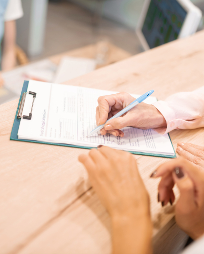 Dental patient signing a form on a clipboard