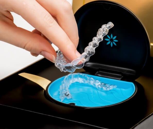 Hand placing an Invisalign aligner in its storage case