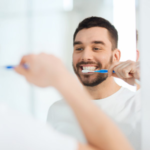 Man smiling while brushing his teeth