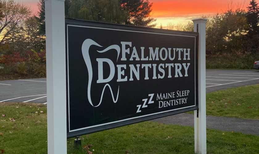 Falmouth Dentistry sign outdoors with sunset in background