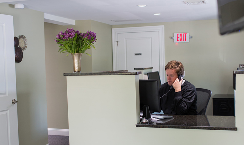 Dental team member sitting at front desk and talking on phone