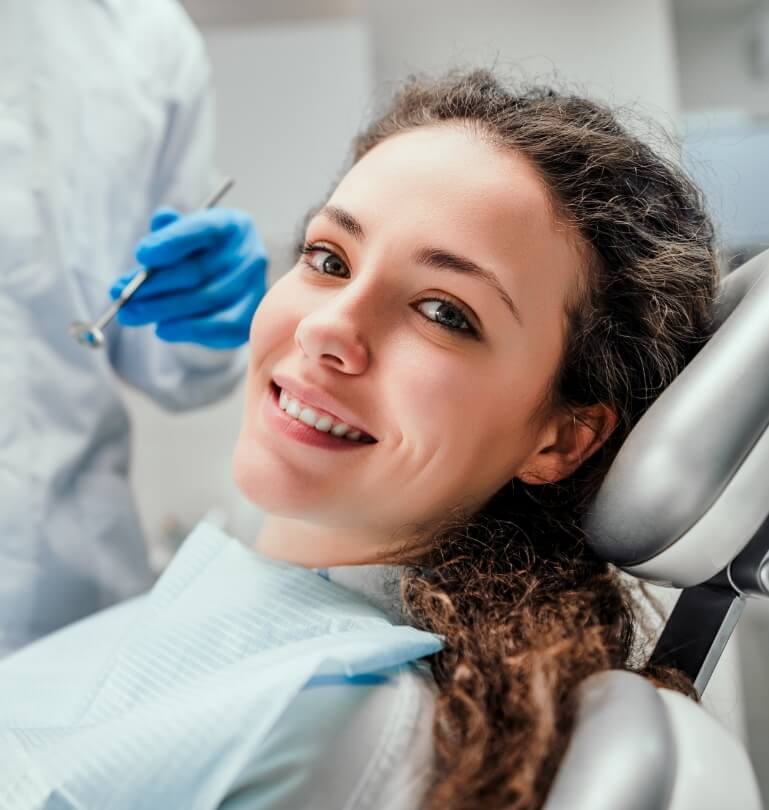 woman with curly hair smiling during preventive dentistry checkup