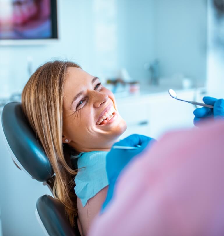 Woman smiling while visiting her dentist for restorative dentistry treatment