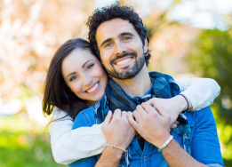 Smiling woman hugging smiling man from behind