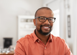 Smiling man with glasses and orange button up shirt