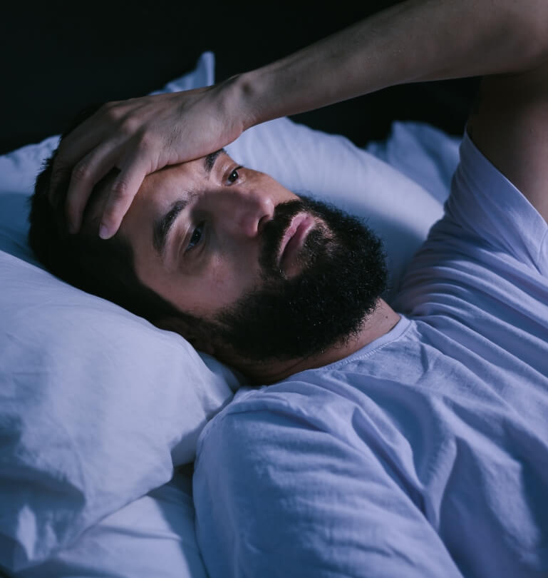 Man lying awake in bed needing sleep apnea treatment in Falmouth