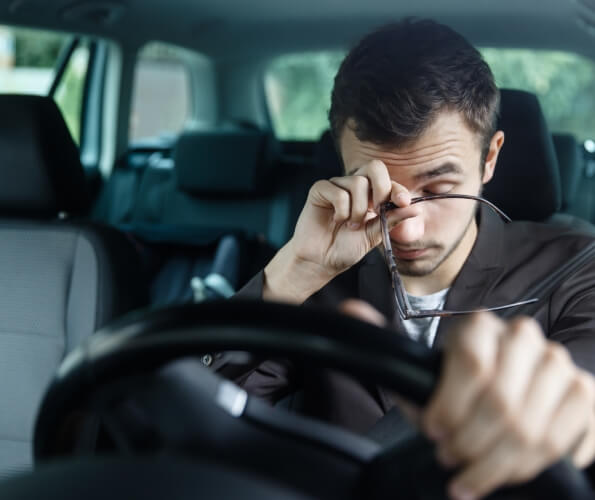 Tired man rubbing his eyes while driving